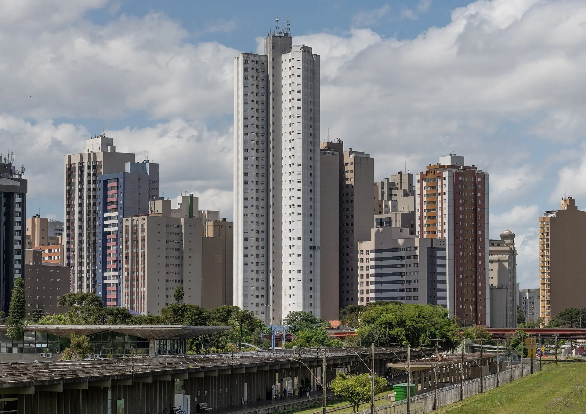 Prédios residenciais de Curitiba atrás da estação rodoferroviária, com araucárias entre os edifícios