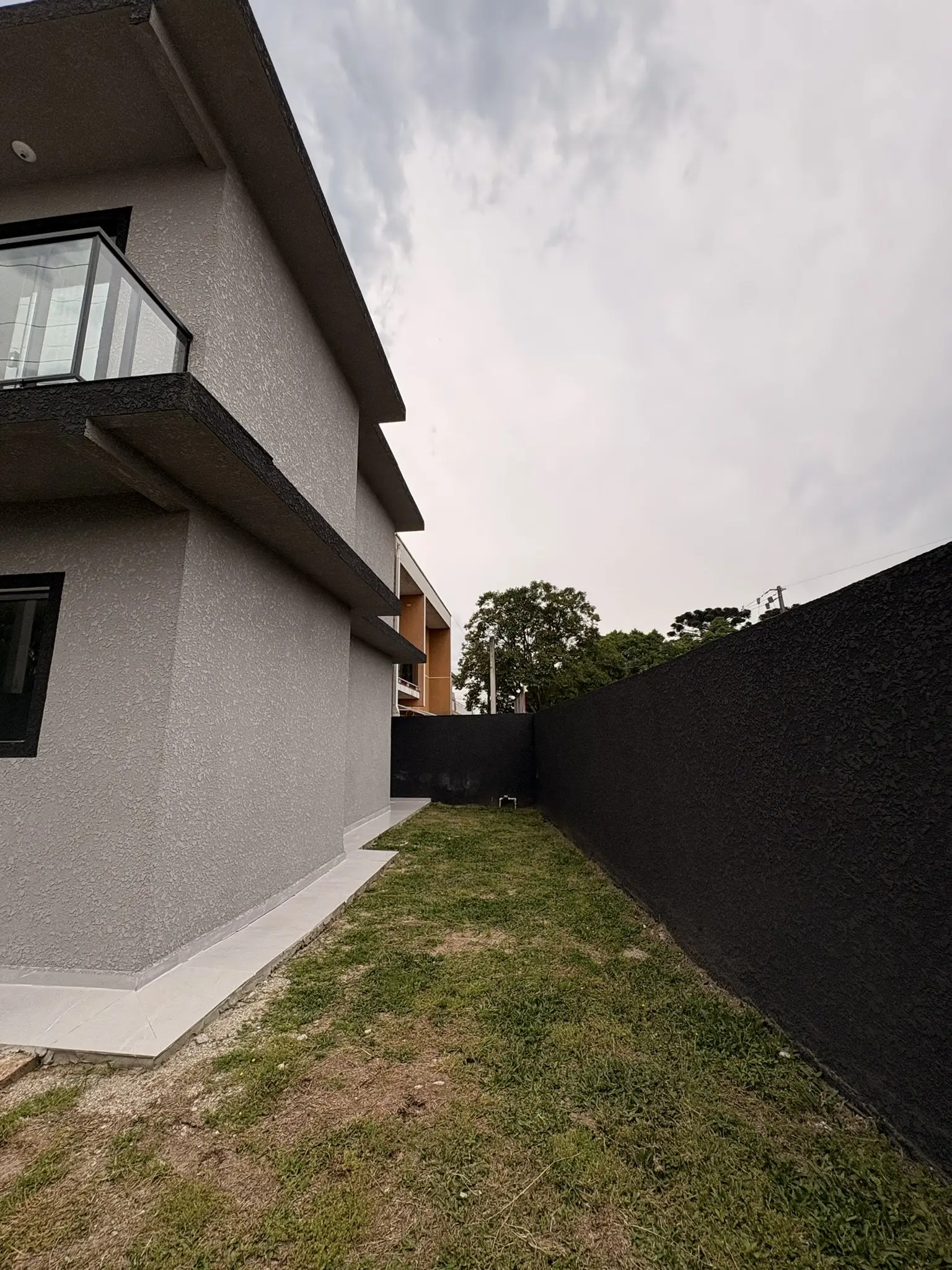 Área externa lateral com gramado e muro